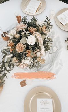 the table is set with plates, napkins and flowers