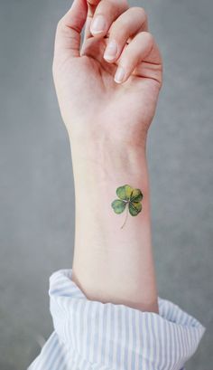 a small four leaf clover tattoo on the wrist