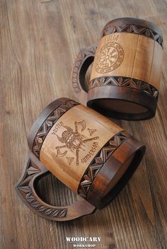 two wooden bracelets with designs on them sitting on top of a wood floor next to each other