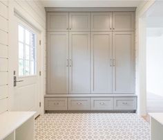 a large walk in closet with white cabinets and drawers next to a window on the wall