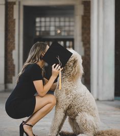 a woman kneeling down next to a dog with a graduation cap on it's head