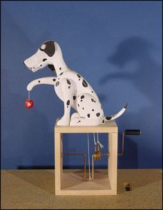 a dalmatian dog statue sitting on top of a wooden table next to a blue wall