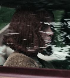 a woman sitting in the back seat of a car with her head out the window