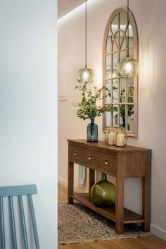 a wooden table with vases on it next to a mirror and bench in a room