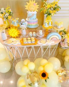 a table topped with lots of yellow and white desserts next to balloons, flowers and sunflowers