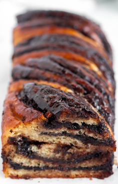 a close up of a sliced cake on a white plate with chocolate swirl toppings