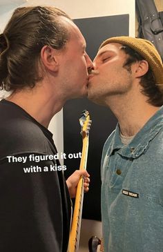 two men are kissing each other with a guitar