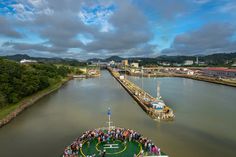 a group of people standing on the side of a boat in a body of water