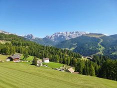 a green field with houses and mountains in the background