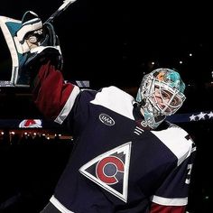 the hockey player is holding up his goalie's helmet