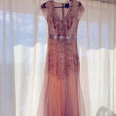 a dress hanging on a hanger in front of a window with curtains behind it