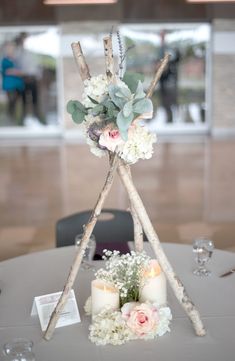 a table with candles, flowers and branches on it is set up for a wedding reception