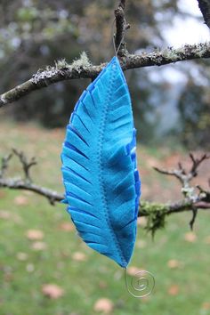 a blue feather hanging from a tree branch