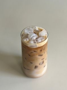 there is a drink with ice on the top and brown liquid in the bottom,