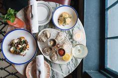 a table topped with plates and bowls filled with food next to a glass door window