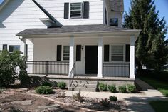 a white two story house with black shutters on the front and side porches