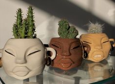 three ceramic masks are sitting on a glass shelf