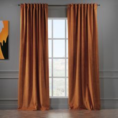 an orange curtain hanging in front of a window with a painting on the wall behind it