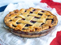 a blueberry pie sitting on top of a white cloth