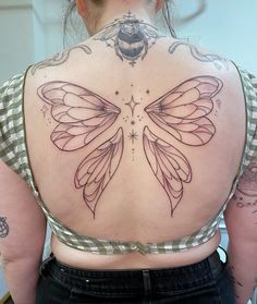 the back of a woman's upper body with tattoos on her shoulders and wings