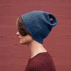 a woman wearing a blue knitted hat in front of a red wall