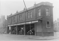 an old black and white photo of a motorcycle shop in front of a brick building