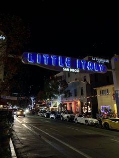 cars are parked on the street in front of some buildings at night with lit up lights