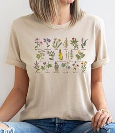 The wildflower t-shirt features multiple types of wildflowers with their names listed, making it perfect for plant lovers, gardeners, and botanical enthusiasts. The t-shirt's design fits perfectly with the cottagecore aesthetic, creating a charming and wholesome vibe. This shirt is an excellent choice for those who appreciate the beauty of nature and want to showcase it in their fashion choices. It's not only cute but also a great way to express your love for the outdoors. shirt details: This classic unisex jersey short sleeve tee fits like a well-loved favorite. Soft cotton and quality print make users fall in love with it over and over again. These t-shirts have-ribbed knit collars to bolster shaping. The shoulders have taping for better fit over time. Dual side seams hold the garment's Nature-inspired Tops With Plant Print For Summer, Botanical Plants Print T-shirt With Relaxed Fit, Nature-inspired Summer Tops With Plant Print, Botanical Relaxed Fit T-shirt With Plant Print, Summer Nature-inspired Tops With Plant Print, Botanical Relax Fit T-shirt With Plant Print, Nature-inspired Cotton Top With Plant Print, Botanical Plants Print Top With Relaxed Fit, Summer Birth Flower Short Sleeve T-shirt