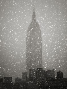 the empire building in new york city is covered with snow as it stands tall above other skyscrapers