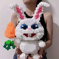 a woman holding a plastic toy made to look like a bunny with carrots in her hands