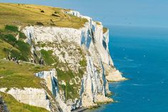 people are standing on the edge of a cliff overlooking the ocean