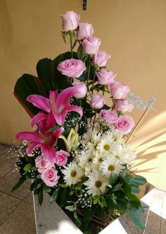 a vase filled with pink and white flowers on top of a tiled floor next to a wall