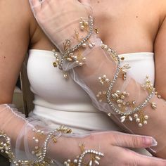 a close up of a person wearing gloves with pearls on it's arms and hands