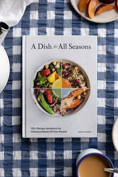 a dish for all seasons cookbook sitting on a table with plates and bowls of food