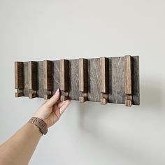 a hand is holding a piece of wood on the wall