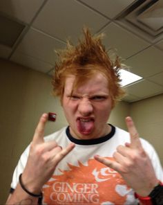 a man with red hair making the middle finger sign while wearing an orange and white t - shirt