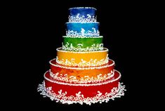 a multi - layer cake is decorated with white lace and colorful frosting, on a black background