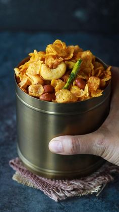 a hand holding a metal container filled with cereal