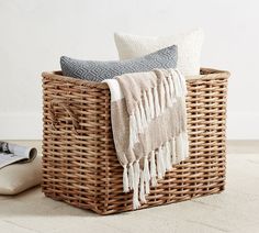 a wicker basket with two pillows and a blanket on it next to a computer mouse