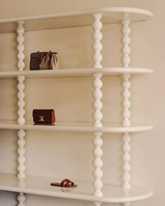 a white shelf with shoes and purses on it