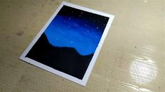 a polaroid photo sitting on top of a wooden table under a blue sky with stars