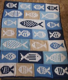 a blue and white crocheted blanket with small fish on the bottom, in front of a tile floor