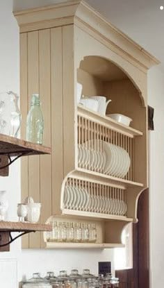 a kitchen filled with lots of white plates and bowls on top of wooden shelves next to cabinets