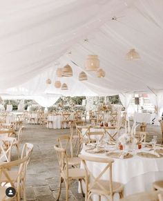 tables and chairs are set up under a white tent