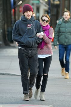 a young man and woman walking down the street with their hands in each other's pockets