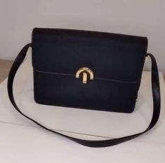 this vintage black leather handbag by luxury Italian designer Andrea Carrano has belt-buckle-look snap closure with engraved signature logo on gold hardware. the strap is adjustable for crossbody or over-the-shoulder and can be tucked inside for use as clutch. interior features two zippered and one card slot compartments. label. Andrea Carrano materials. leather, fabric vintage condition code. excellent (see ABOUT section for more detail or contact us) measurements in inches body height. 7.5 str Black Leather Handbag, Black Leather Handbags, Signature Logo, Kate Spade Crossbody, Crossbody Shoulder Bag, Belt Buckles, Baguette, Gold Hardware, Vintage Black