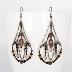 This drop chandelier earring consists of multiple glass faceted and seed beads with the stunning purple oval centre bead. Offsetting the glass are the chain supports and wiring. Gorgeous worn as a pair but stunning when worn as a feature or statement earring! * Length is 8 cm (3 inches) * Width at widest point is 4 cm (1.5 inches) * Each earring weighs 5g * Shepherd hook for pierced ears * Glass beading * All handmade You will not be disappointed with this addition to your earring wardrobe. Beaded Czech Glass Chandelier Drop Earrings, Bohemian Dangle Teardrop Earrings With Faceted Beads, Elegant Teardrop Chandelier Earrings With Colorful Beads, Beaded Metal Teardrop Chandelier Earrings, Bohemian Chandelier Dangle Earrings With Faceted Beads, Bohemian Chandelier Earrings With Faceted Beads, Bohemian Style Chandelier Earrings With Faceted Beads, Dangle Beaded Earrings With Faceted Metal Beads, Purple Czech Glass Beaded Earrings With Dangling Beads