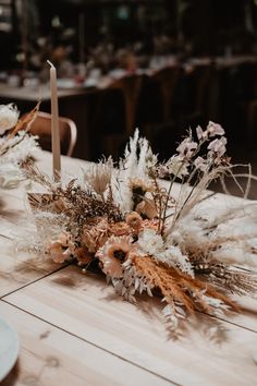 an arrangement of dried flowers and candles on a table