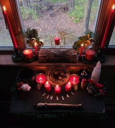 candles are arranged on the window sill in front of a christmas wreath and other decorations