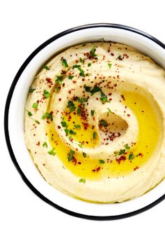 hummus in a white bowl topped with olives and parmesan sprinkles